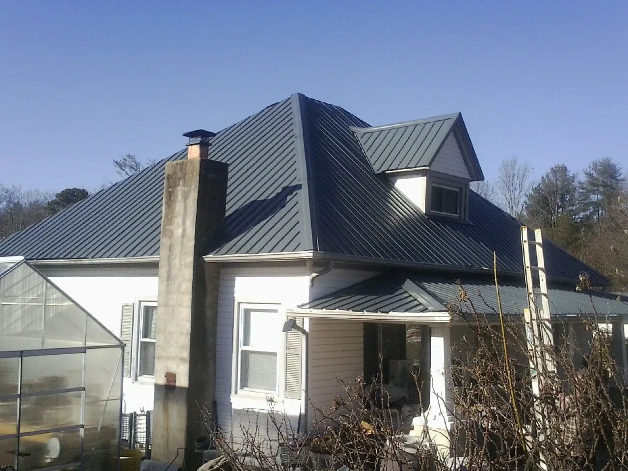 Dark blue standing seam metal roof on a white farmhouse with dormer — Slate & Tile Roof Repair by Roofing Brothers in Allenwood