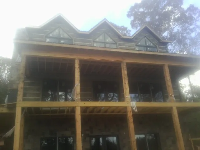 Dormers and porch framing on a large log home under construction — Roof Coating work by our crew in Allenwood