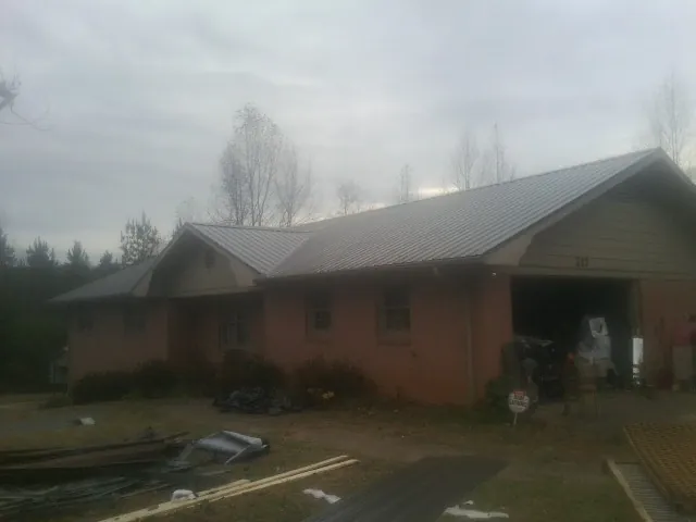Gray metal roof on a stucco house with an attached garage in Allenwood